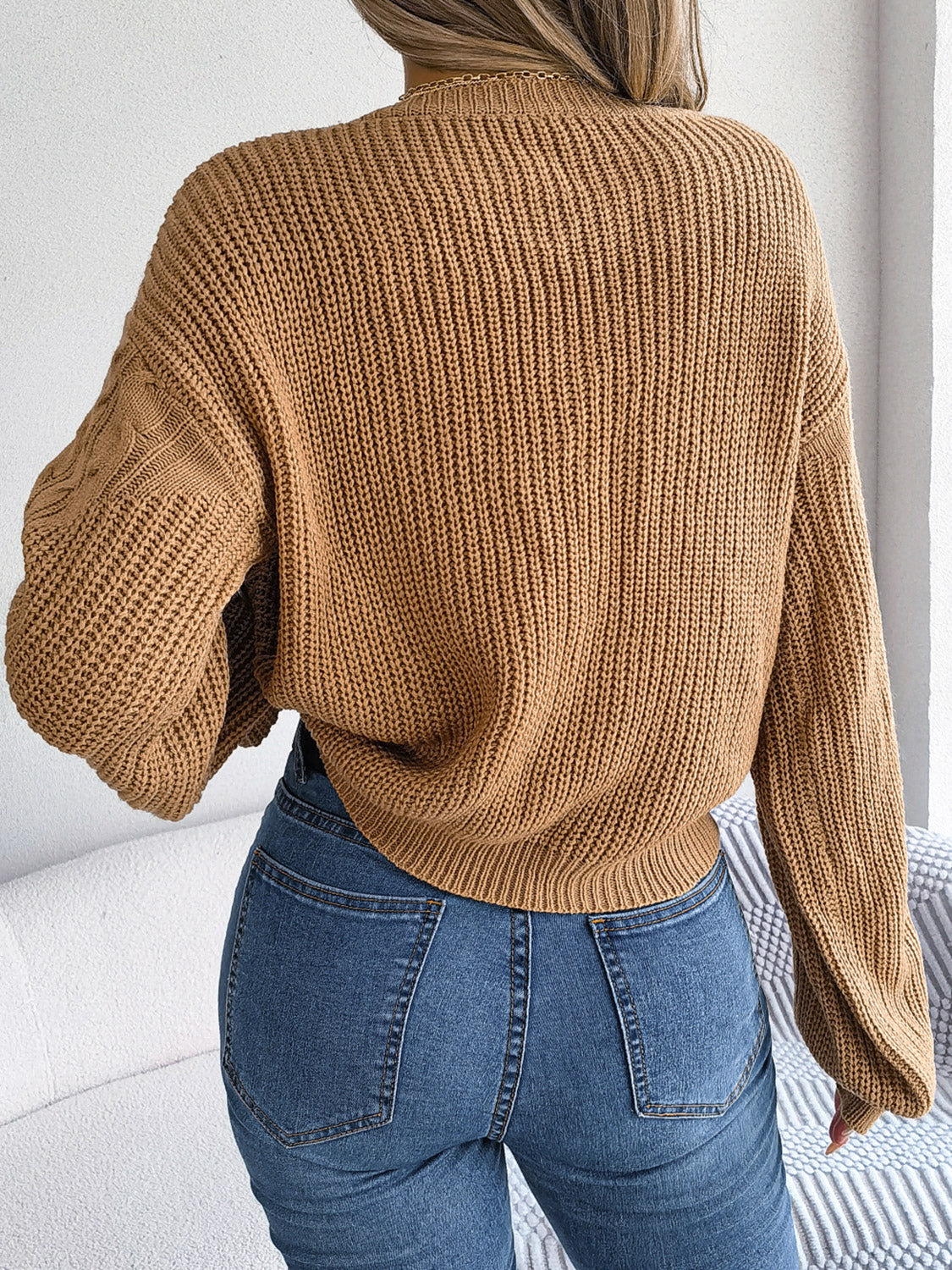 Back side of cable-knit sweater showing relaxed fit and stitching detail