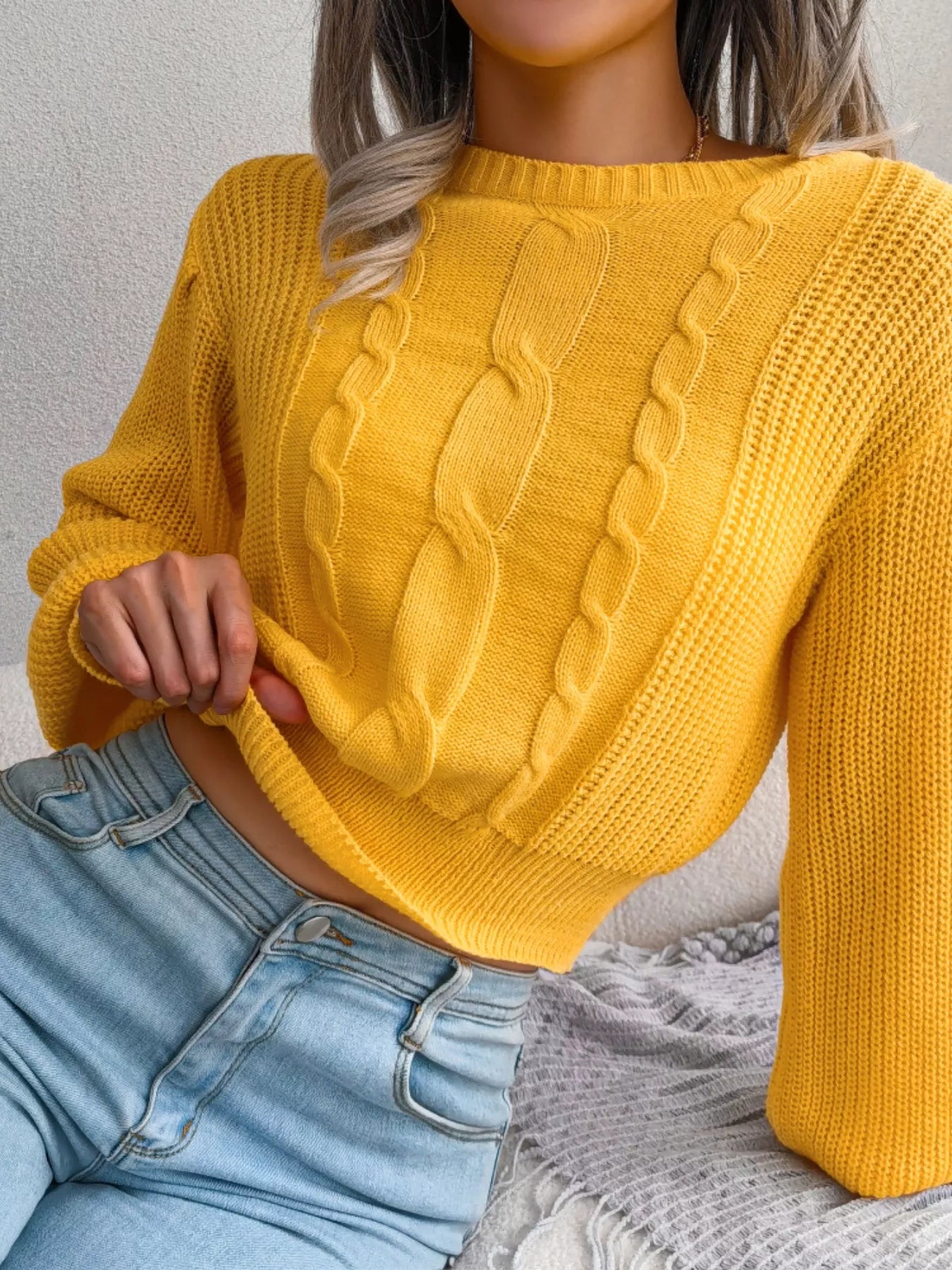 Angled view of cable knit round neck cropped sweater